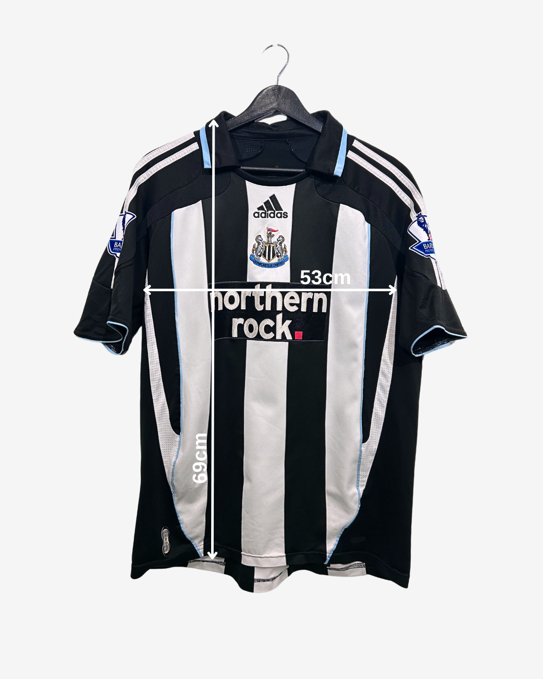 Black and white striped sports jersey with Adidas logo on a hanger, measurement label included.