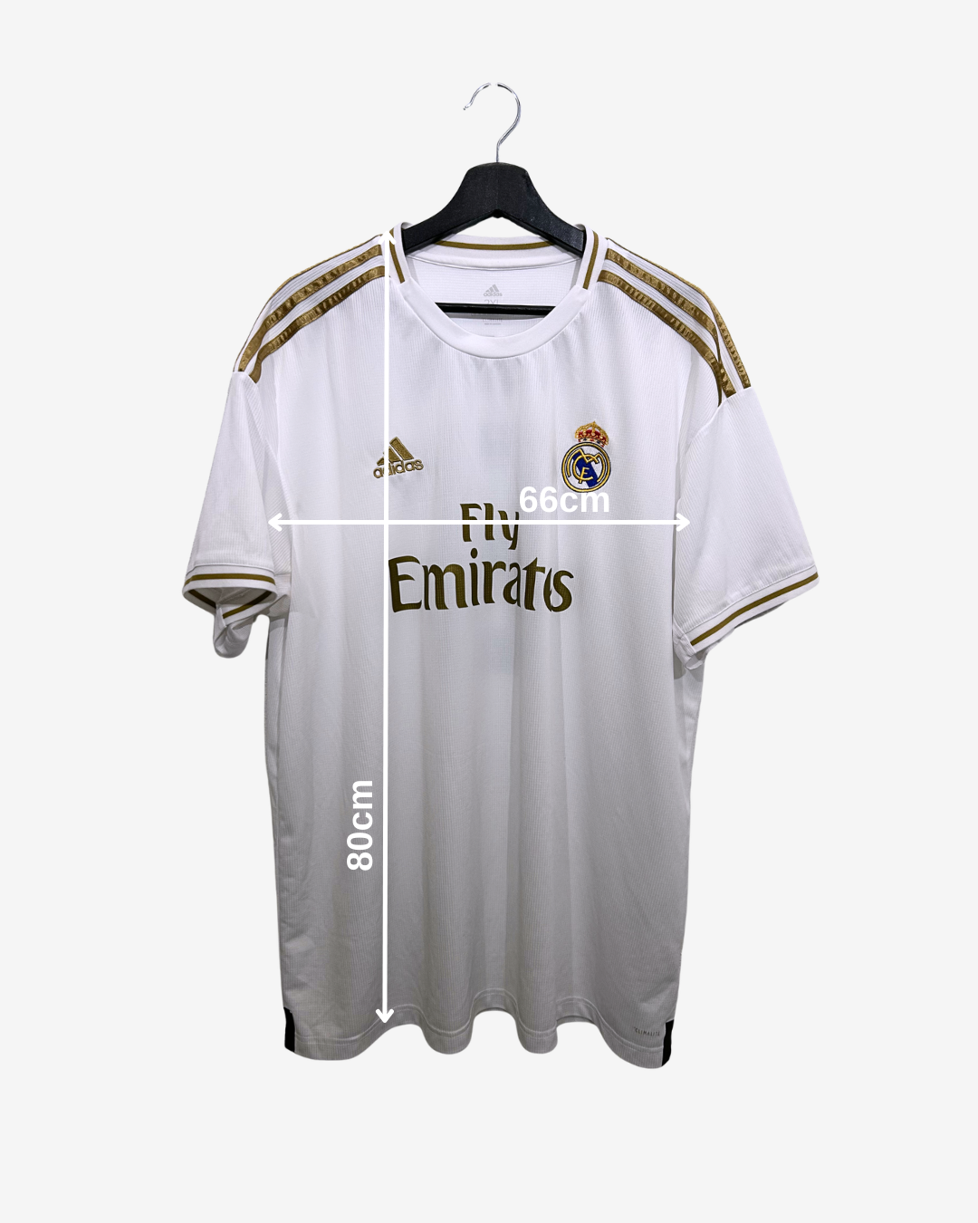 White sports jersey with gold accents on a hanger, featuring Adidas and Fly Emirates logos, with measurements indicated.