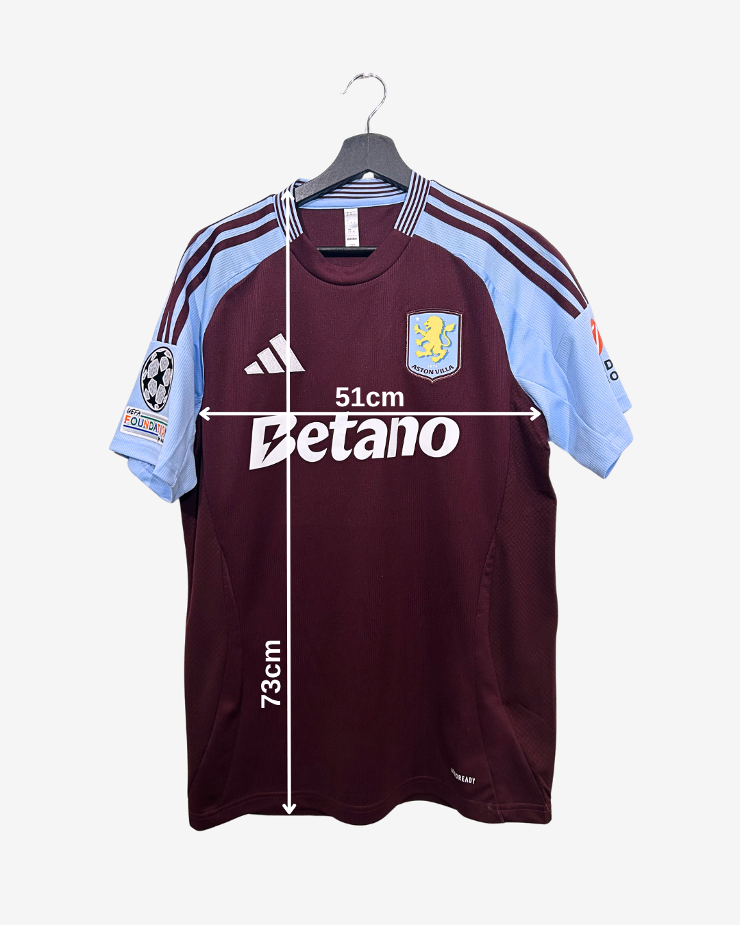Maroon sports jersey with light blue sleeves on a hanger, featuring Adidas and Betano logos.