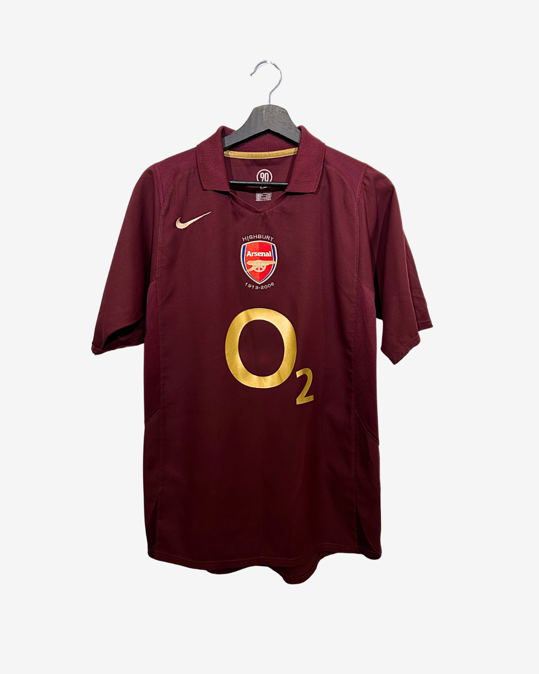 Maroon sports jersey with Arsenal logo and 'O2' branding on a hanger against a white background