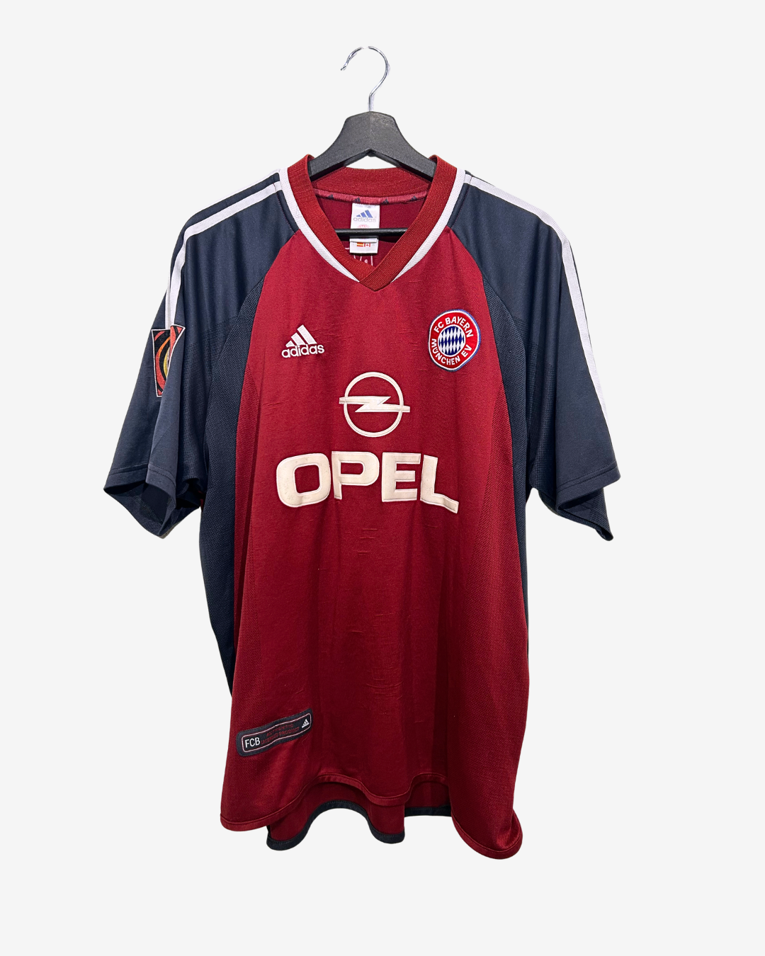 Red and navy sports jersey with Opel and Adidas logos on a hanger against a white background