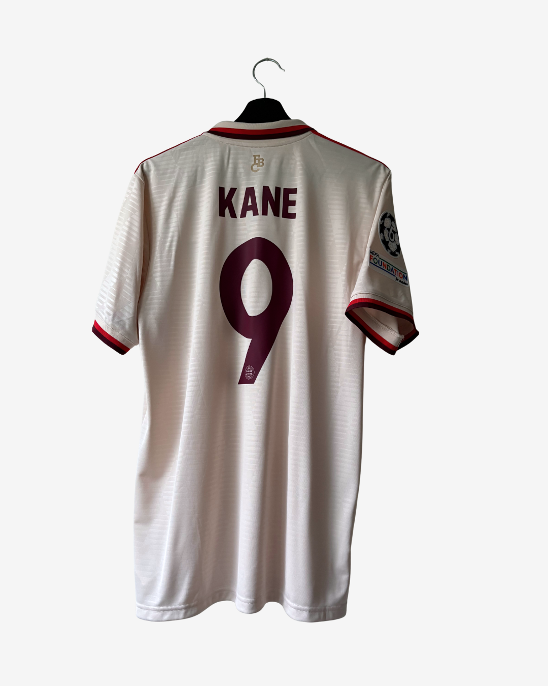 A white short-sleeve sports jersey hanging on a black hanger against a light gray background. The back of the jersey shows the name KANE in maroon above a large maroon number 9.