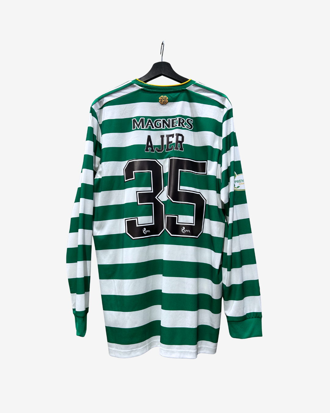A Celtic long-sleeve football jersey with green and white horizontal stripes, featuring the back view with 'MAGNERS', 'AJER', and the number '35' printed in black. The jersey is hanging on a black hanger against a light gray background.