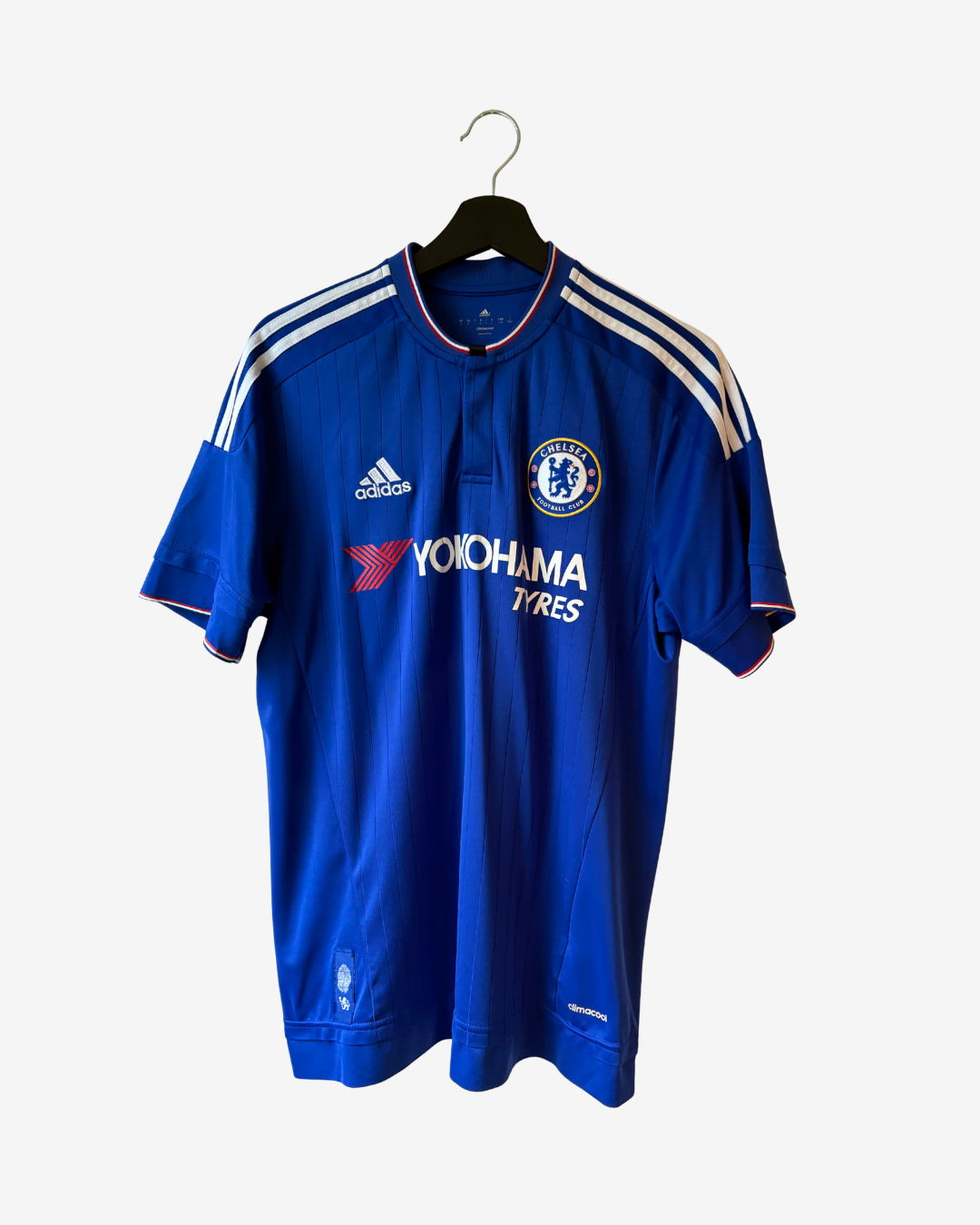 A blue Chelsea football jersey by Adidas, featuring the Yokohama Tires sponsor logo, hanging on a black hanger against a light gray background.