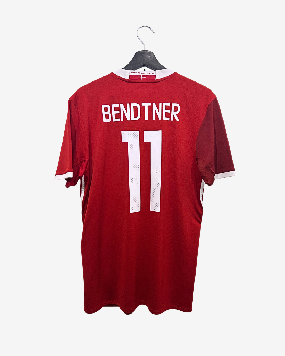Red sports jersey with 'Bendtner' and number '11' on a hanger against a white background