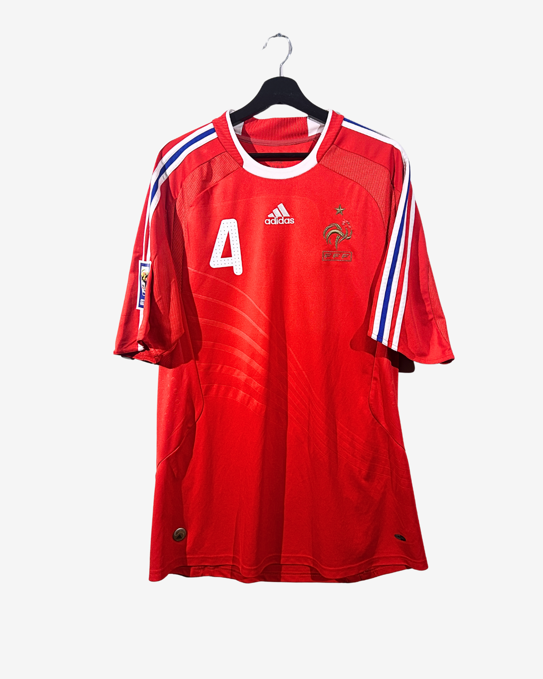 Red sports jersey with number 4 and Adidas logo on a hanger against a white background