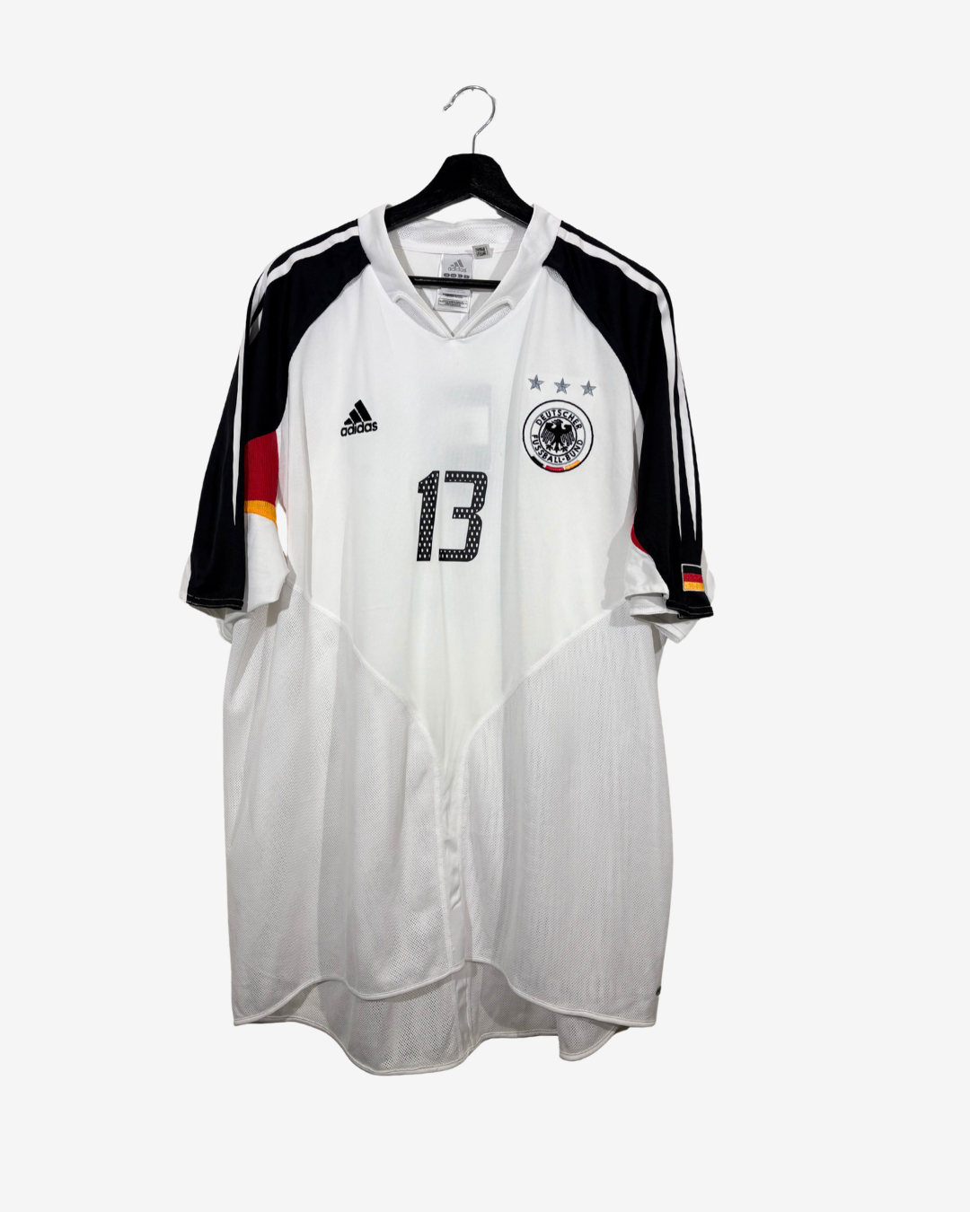 A white Germany national team soccer jersey with black and red accents, featuring the Adidas logo and the DFB crest, hanging on a black hanger against a light gray background.