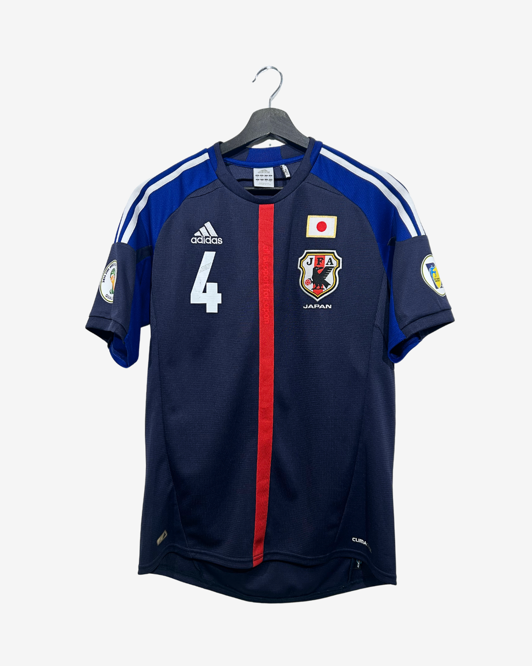 A navy blue Adidas Japan national football team jersey with the number 4, hanging on a black hanger against a light gray background.