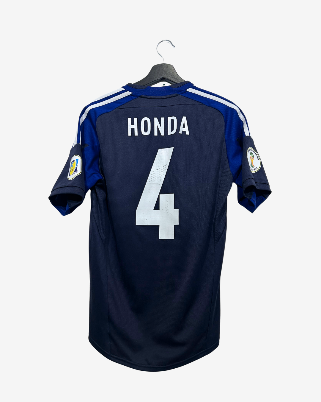 A navy blue Vancouver Island Warriors soccer jersey with 'HONDA' and the number '4' printed on the back, hanging on a black hanger against a light gray background.