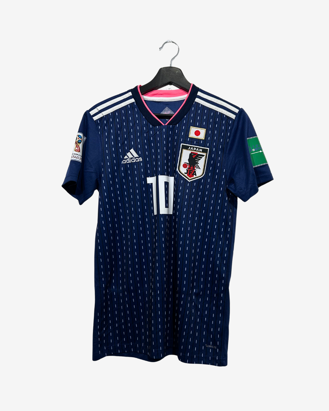 A navy blue Japan national football team jersey with white dotted patterns, featuring the number 10 on the front, an Adidas logo, and a Japan crest, hanging on a black hanger against a light gray background.
