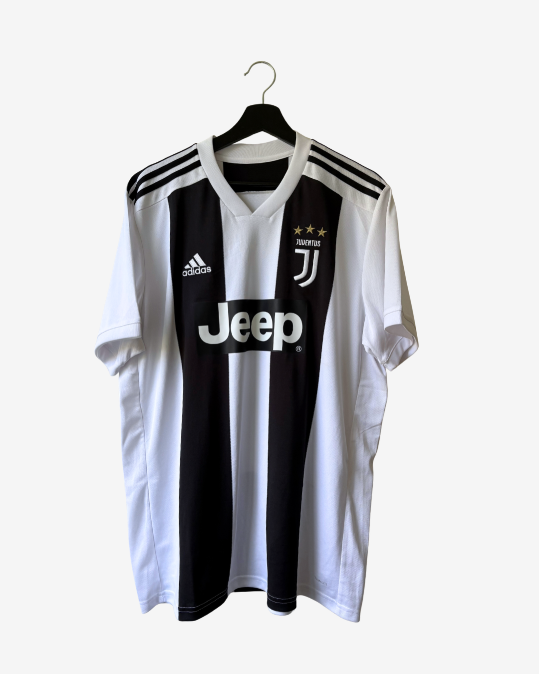 A vintage Adidas Juventus home soccer jersey with black and white vertical stripes, featuring the Jeep sponsor logo, Adidas logo, and Juventus crest, hanging on a black hanger against a light gray background.