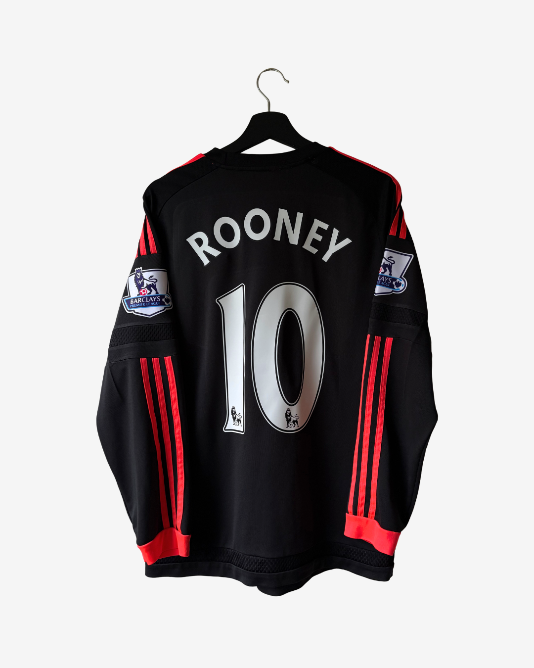 Black long-sleeve soccer jersey with 'ROONEY' and number '10' printed on the back, hanging on a black hanger against a light gray background. The jersey features red stripes down the sleeves and red trim at the cuffs.