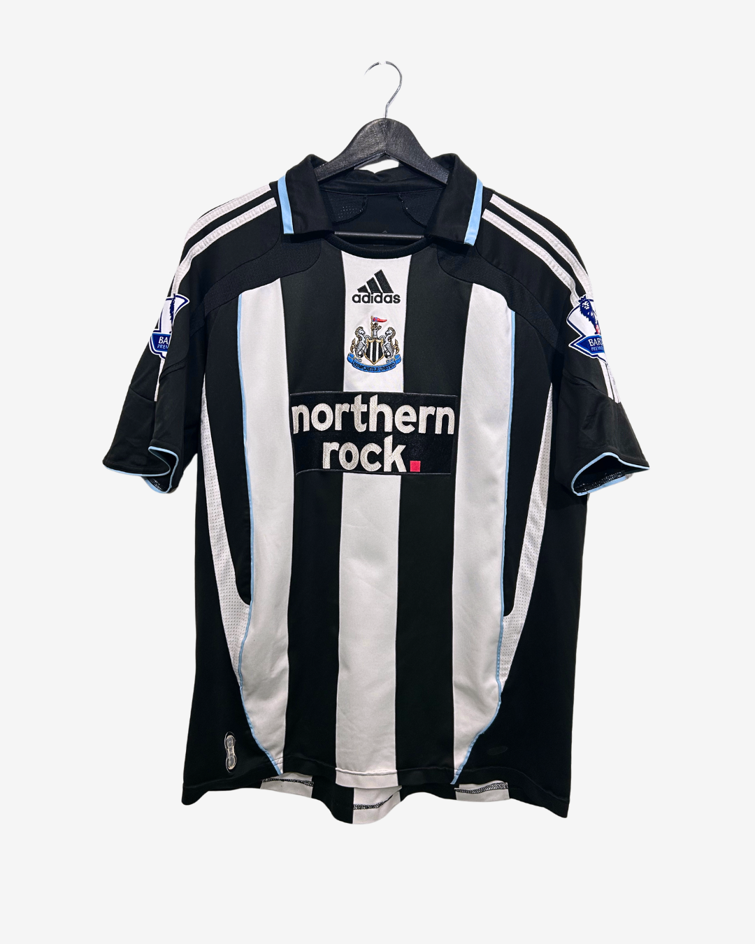 Black and white striped sports jersey with Adidas logo on a hanger against a white background