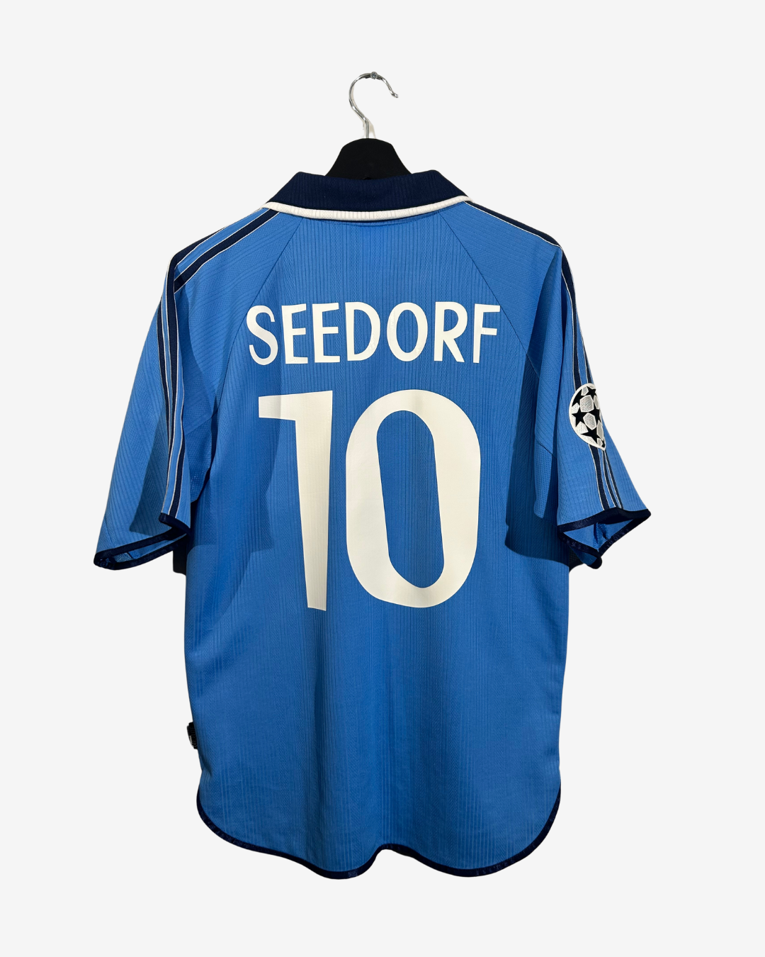 A blue soccer jersey with 'SEEDORF' and the number '10' printed on the back, hanging on a black hanger against a light gray background.