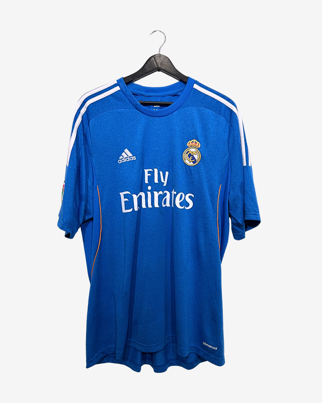 Blue sports jersey with Adidas and Fly Emirates logos on a hanger against a white background