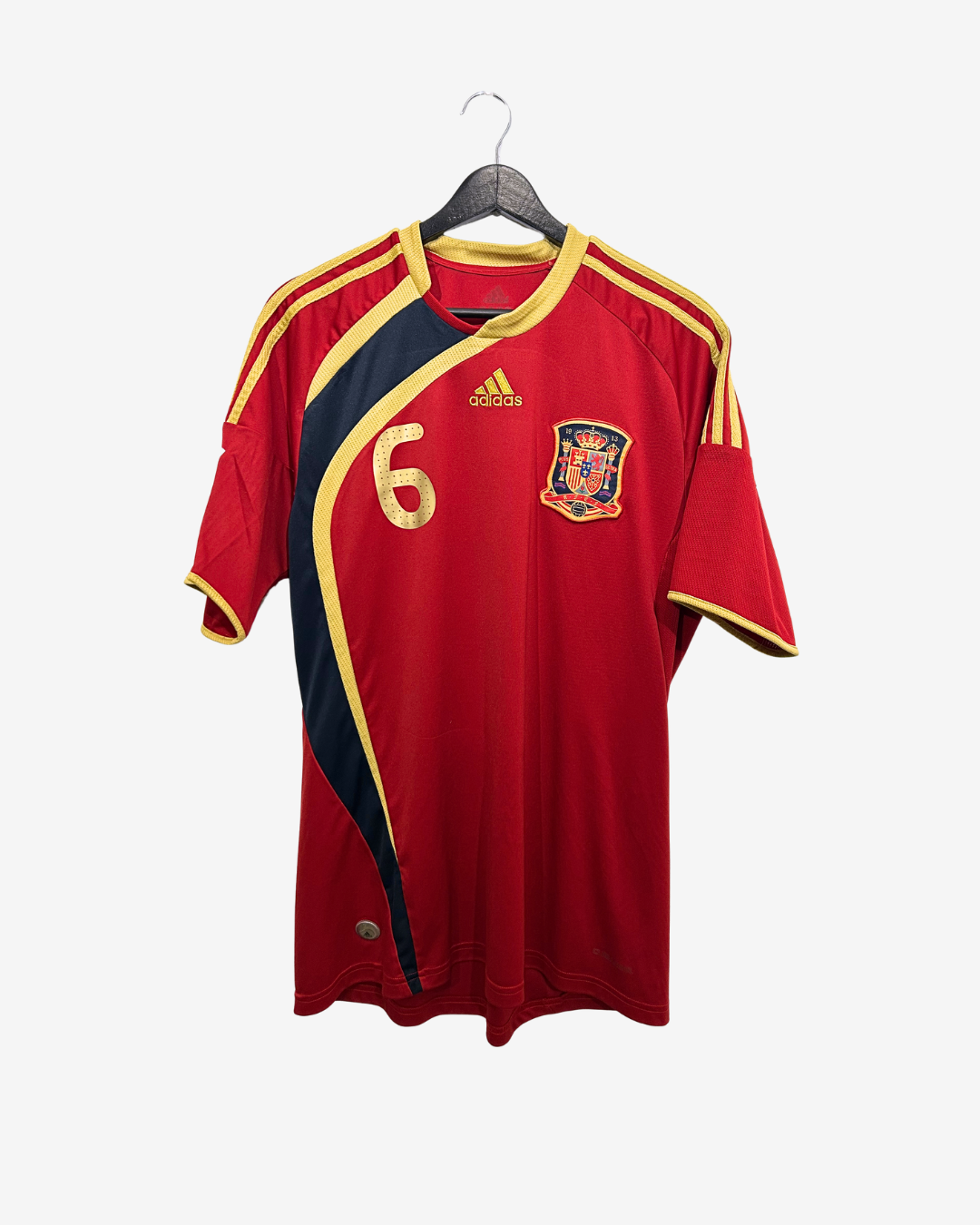 Red sports jersey with gold accents on a hanger against a white background