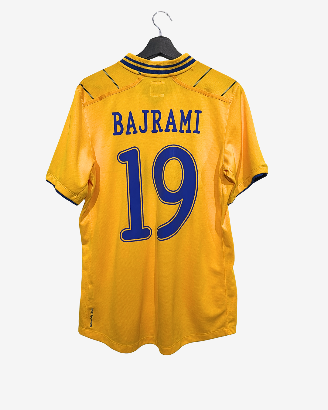 Yellow sports jersey with 'BAJRAMI' and number '19' on a hanger against a white background