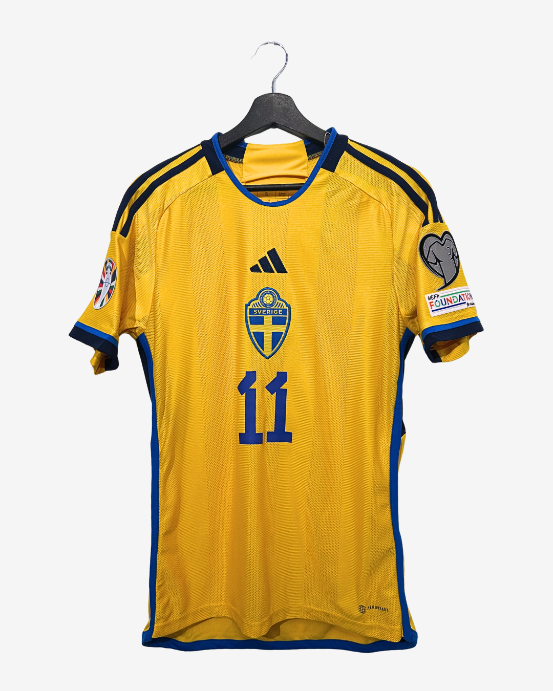 Yellow sports jersey with blue accents on a hanger against a white background