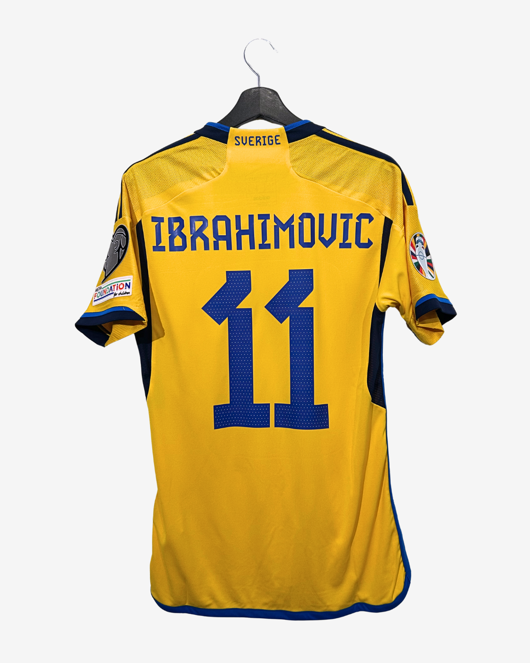 Yellow sports jersey with blue numbering and text on a hanger against a white background