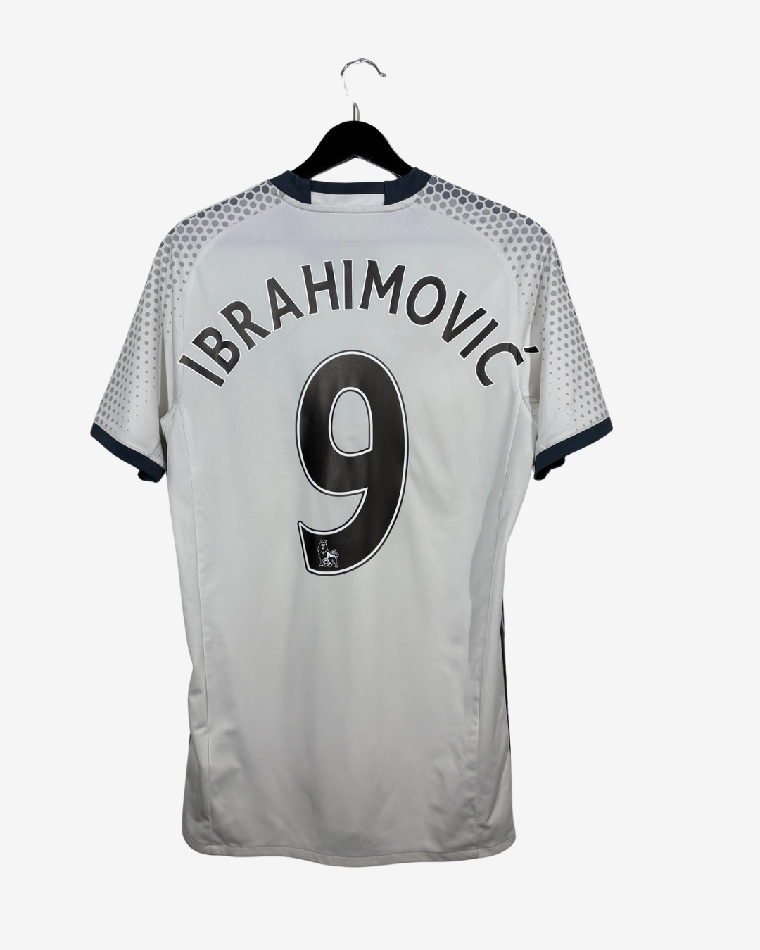 A white short-sleeve football jersey with 'IBRAHIMOVIC' and the number '9' printed in black on the back, hanging on a black hanger against a light gray background.
