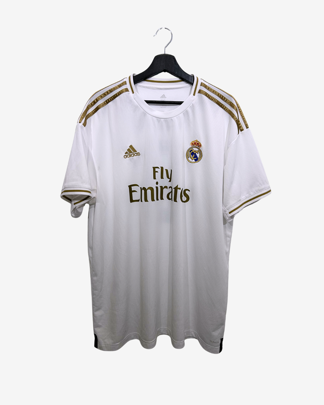 White soccer jersey with gold accents on a hanger against a white background