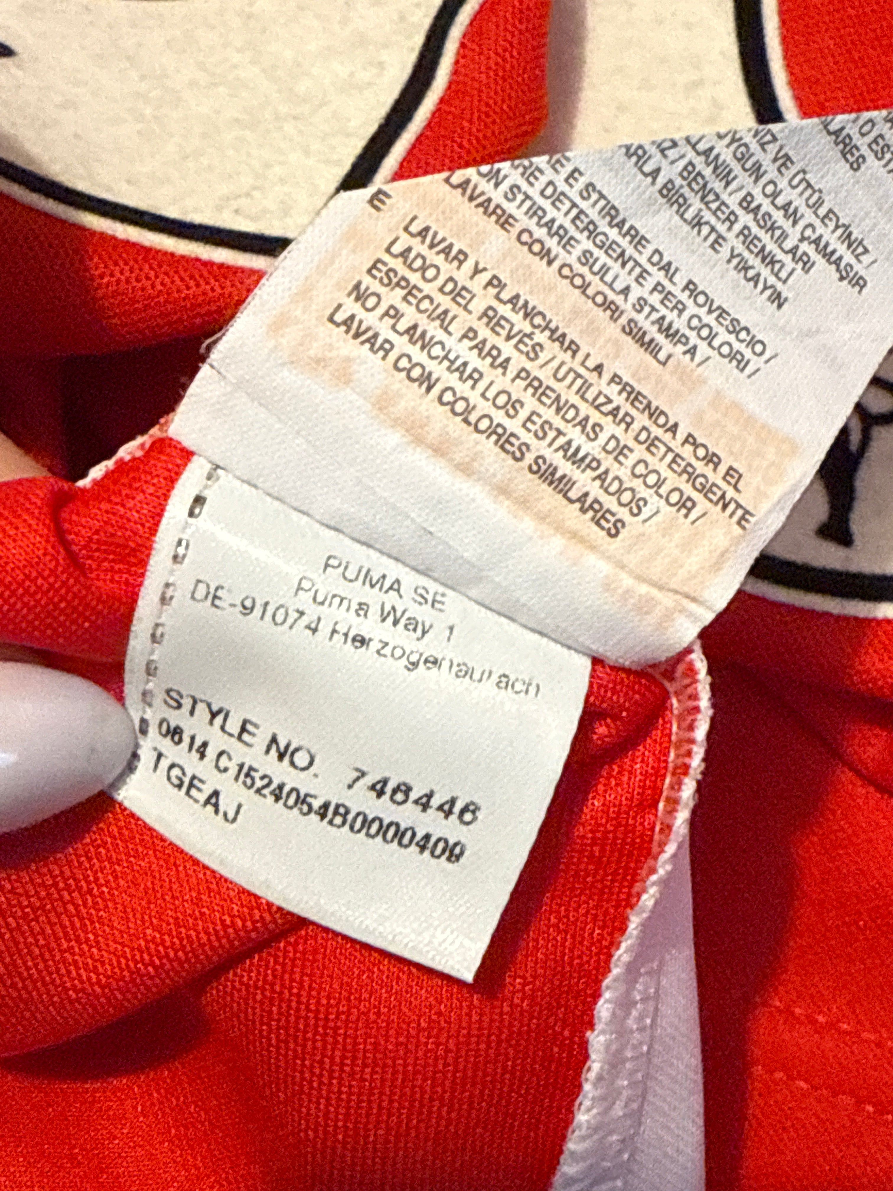 Close-up of a clothing label on a red garment with visible text.