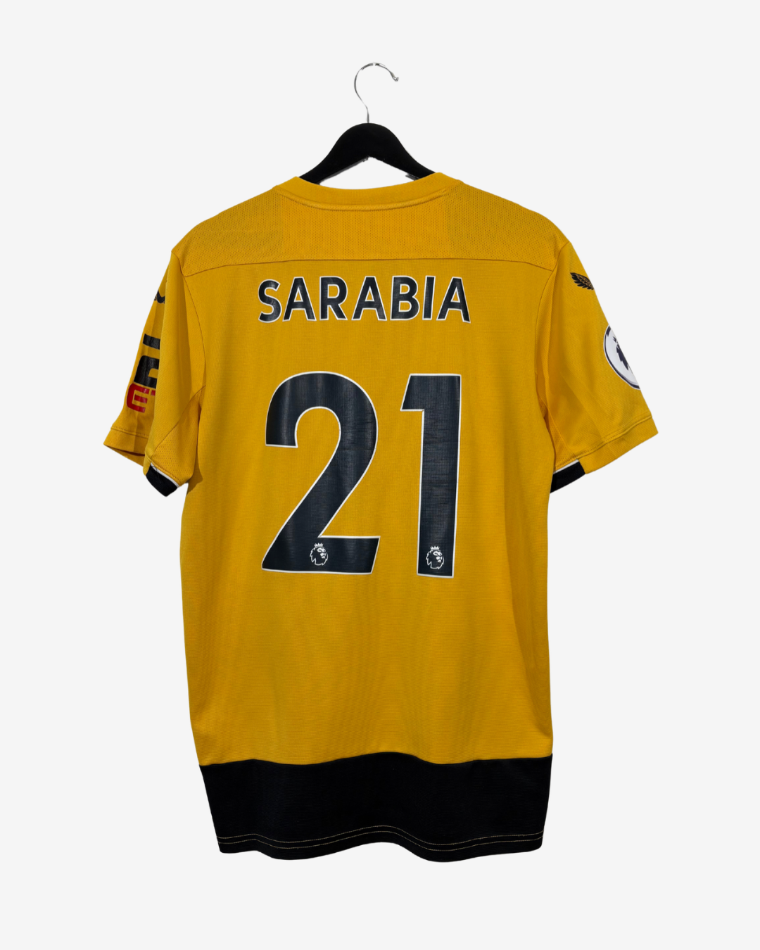 A yellow soccer jersey with 'SARABIA' and the number '21' printed in navy blue on the back, hanging on a black hanger against a light gray background.