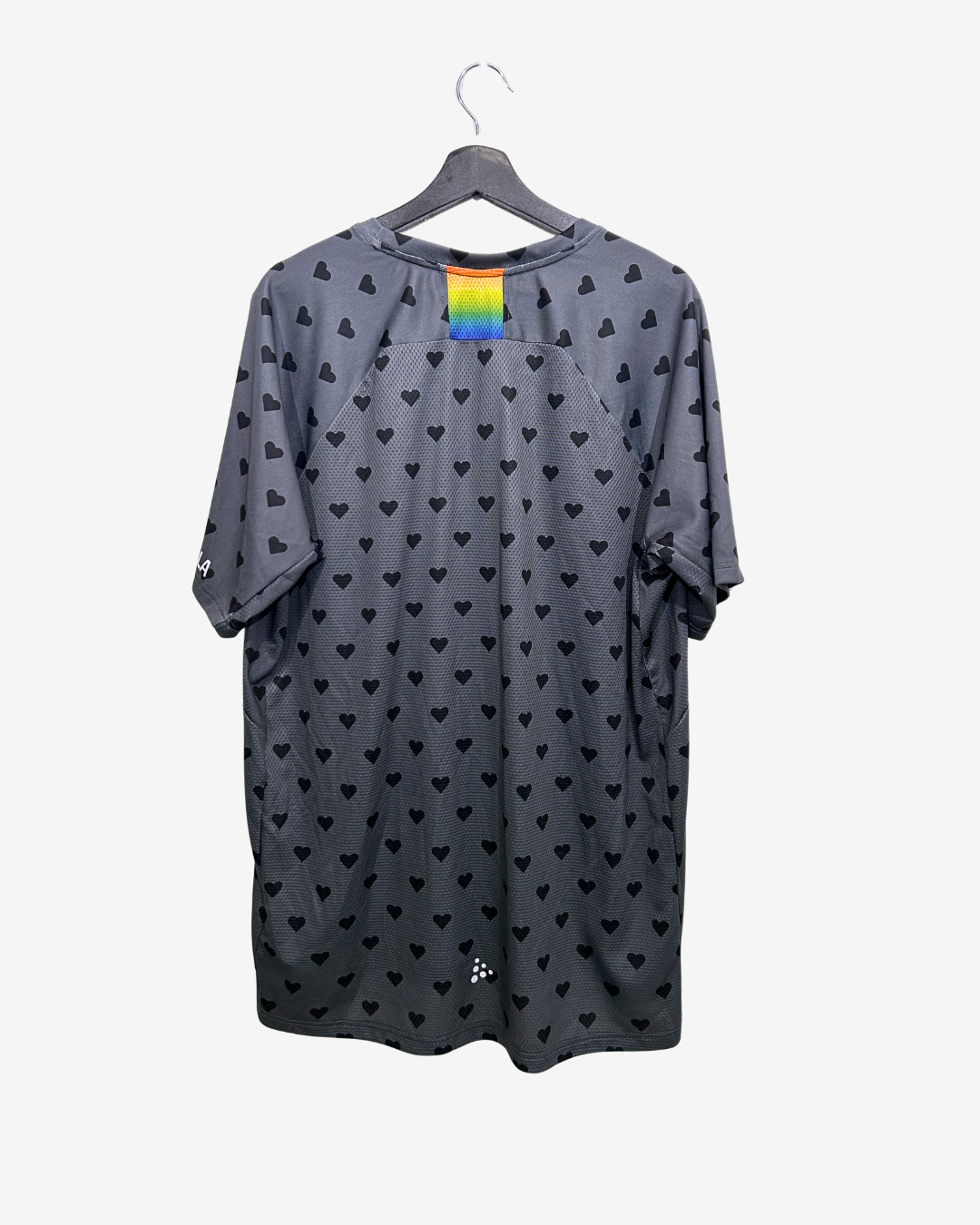 Gray t-shirt with black heart patterns on a hanger against a white background