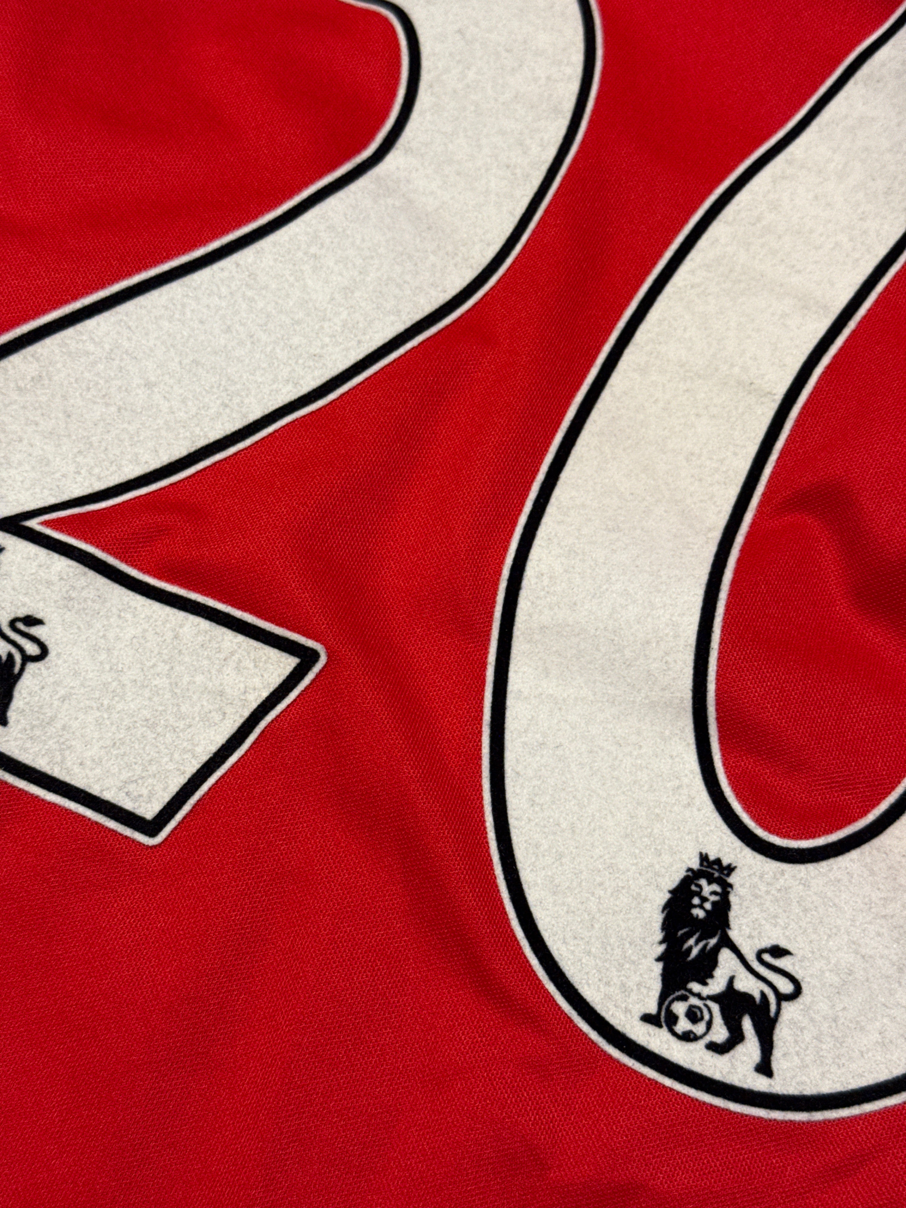 Close-up of a red sports jersey with white lettering and a logo.