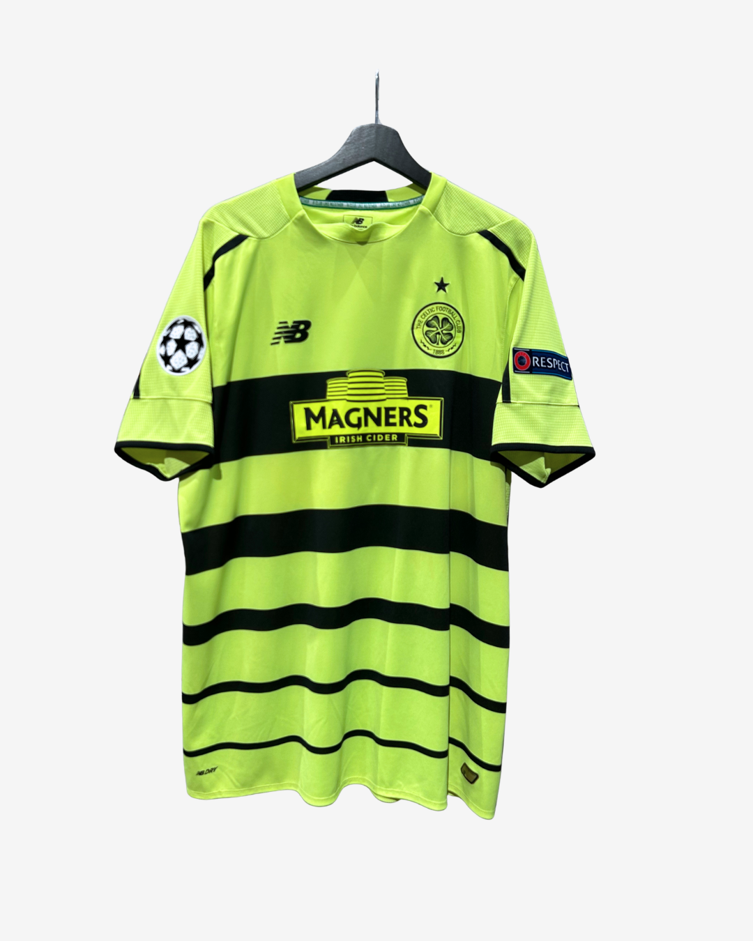 A neon yellow-green and black striped Ajax Amsterdam soccer jersey by New Balance, hanging on a black hanger against a light gray background. The jersey features a black horizontal stripe across the chest with the 'MAGNERS' sponsor logo, the Ajax club crest, and the New Balance 'NB' logo on the sleeves.