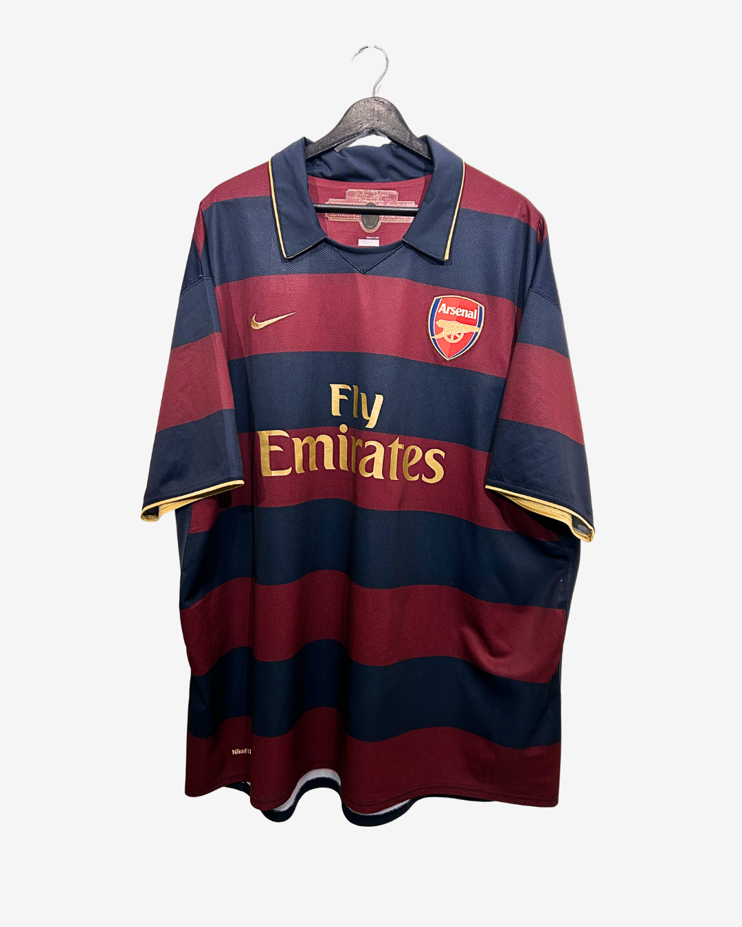 Arsenal football jersey with red and navy stripes on a hanger