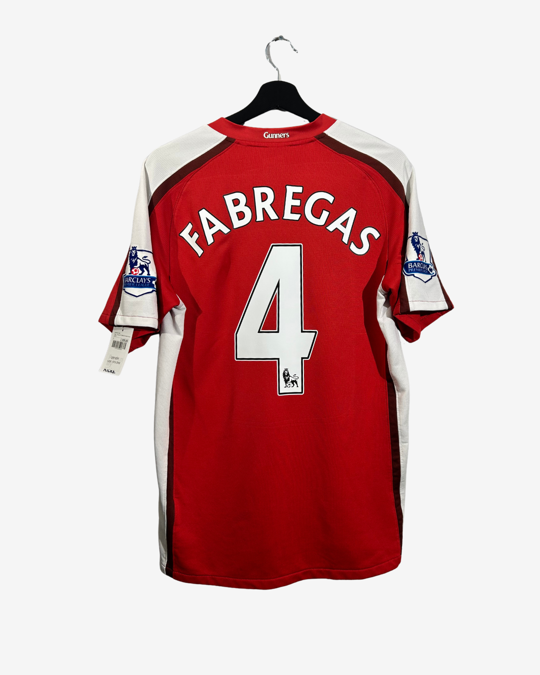 A red and white Arsenal soccer jersey with 'FABREGAS' and the number '4' printed on the back, hanging on a black hanger against a light gray background.