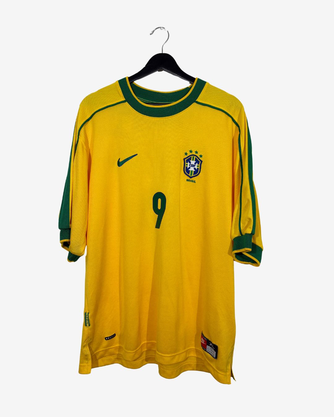 A vintage yellow Brazil national football team jersey with green trim, featuring the number 9 on the front, a green Nike swoosh, and the CBF crest, hanging on a black hanger against a light gray background.