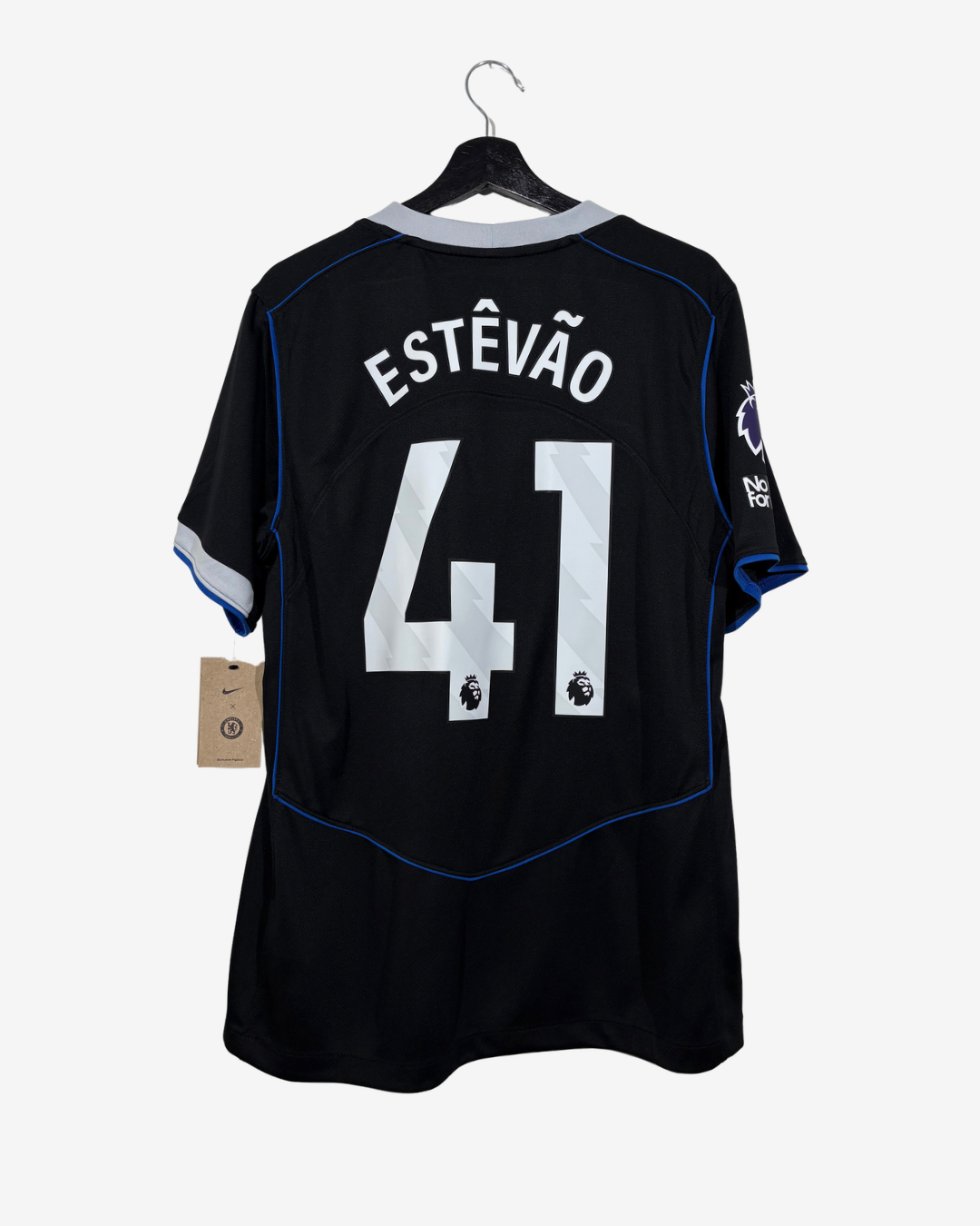 Black Chelsea football jersey shown from the back on a hanger, featuring 'ESTÉVÃO' and the number '41' in white, with blue piping and a paper tag attached.