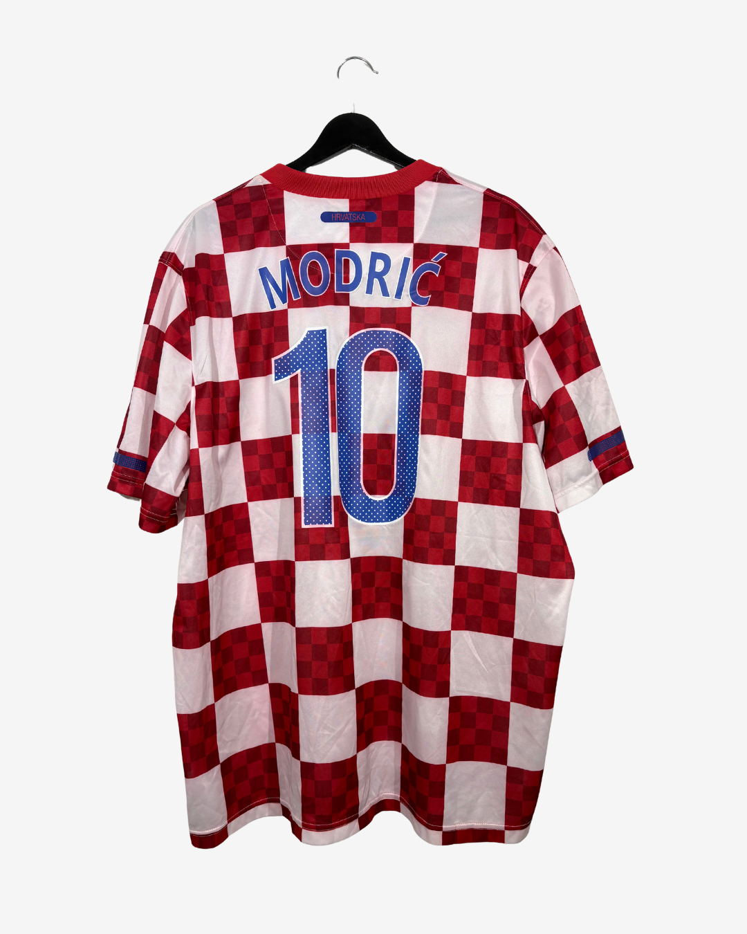 A red and white checkered Croatia national team jersey with 'MODRIĆ' and the number '10' printed on the back, hanging on a black hanger against a light gray background.