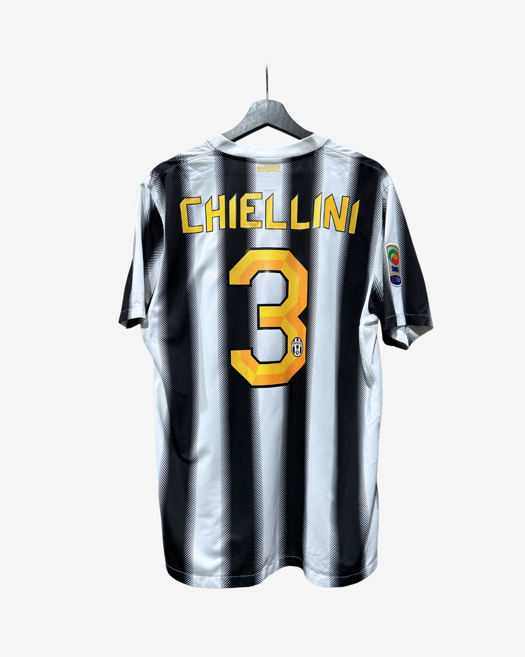 Back view of a black and white vertically striped soccer jersey hanging on a hanger, with 'CHIELLINI' and the number '3' in yellow on the back.
