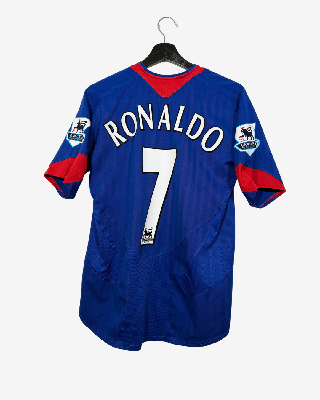 A blue and red soccer jersey with 'RONALDO' and the number '7' on the back, hanging on a black hanger against a light gray background.