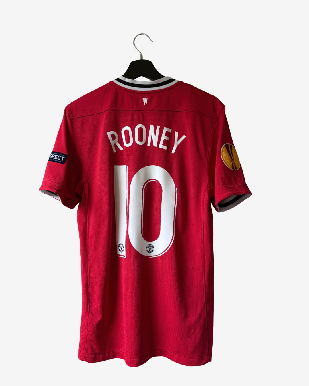 A red Manchester United short-sleeve soccer jersey with 'ROONEY' and the number '10' printed in white on the back, hanging on a black hanger against a light gray background.