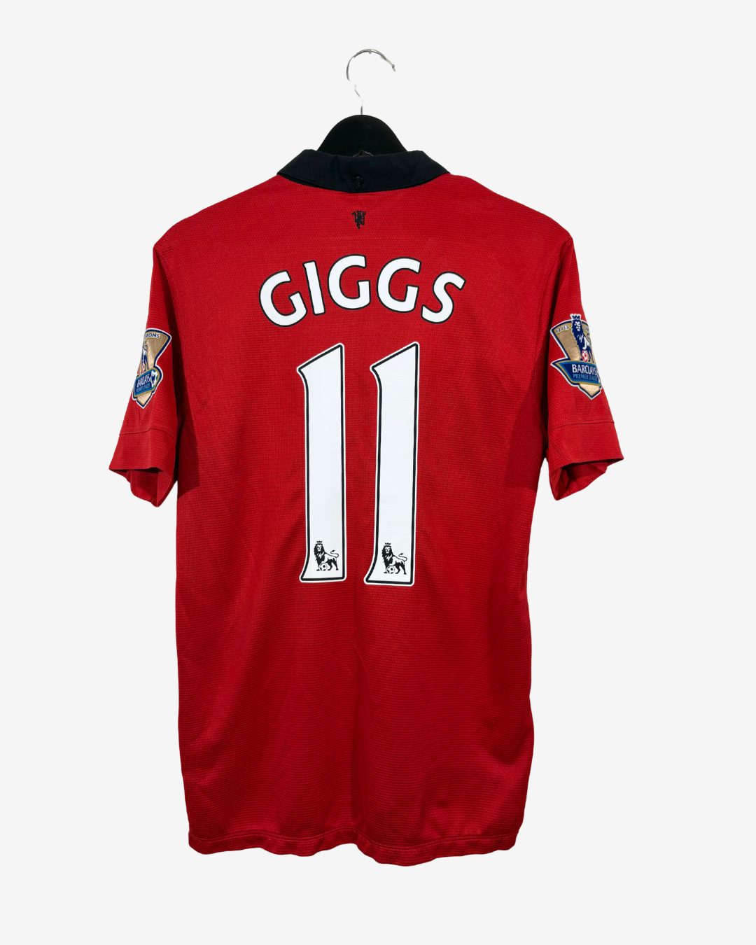 A red short-sleeve football jersey hanging on a black hanger against a light gray background. The back of the jersey features the name 'GIGGS' and number '11' in white with black outlines