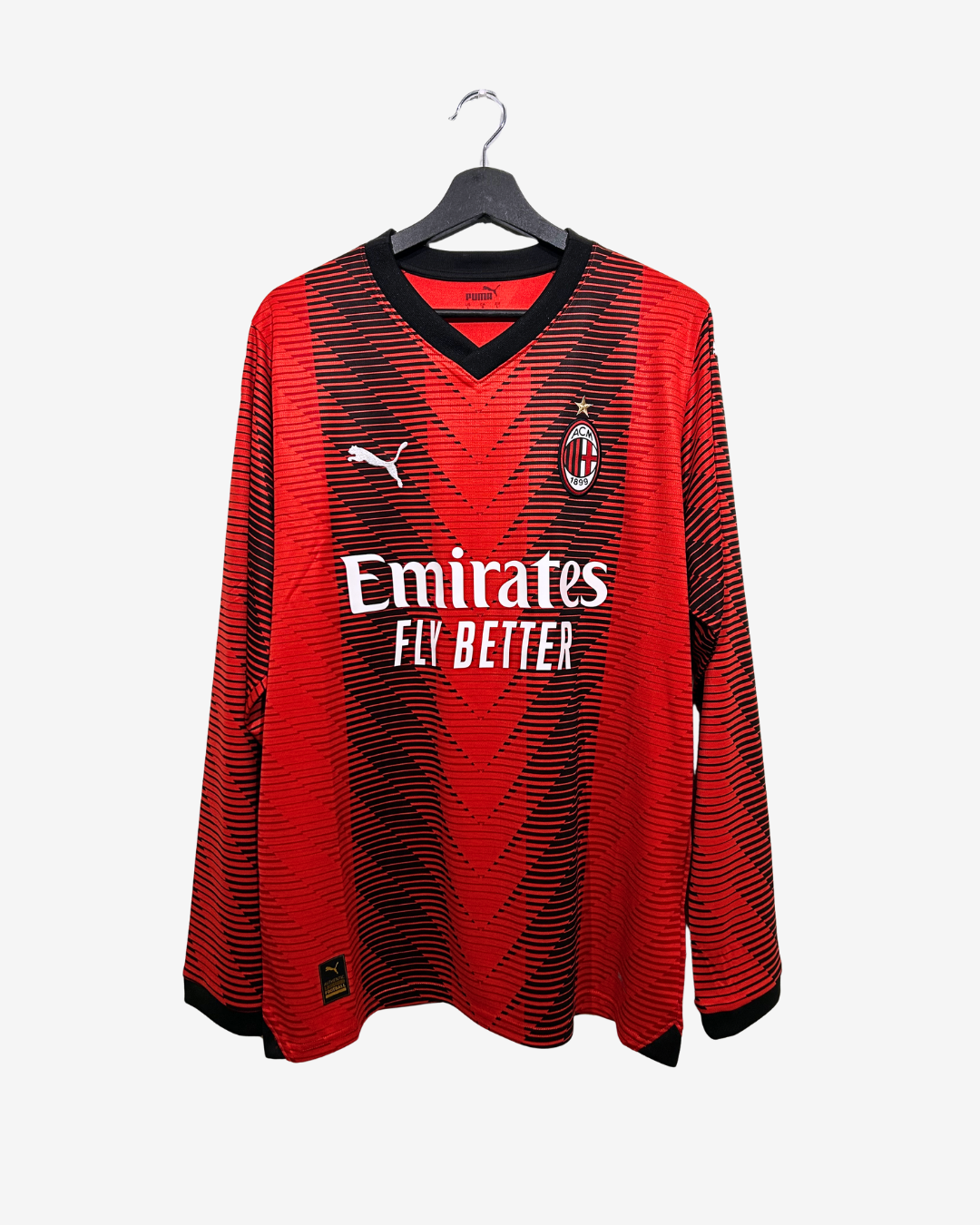 Red sports jersey with Emirates logo on a hanger against a white background