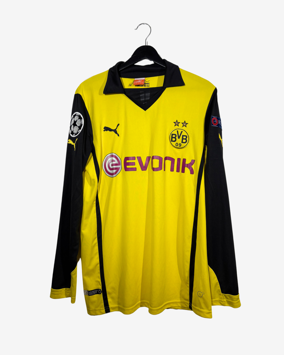 A yellow and black long-sleeve Borussia Dortmund soccer jersey with the Evonik sponsor logo, displayed on a black hanger against a light gray background.