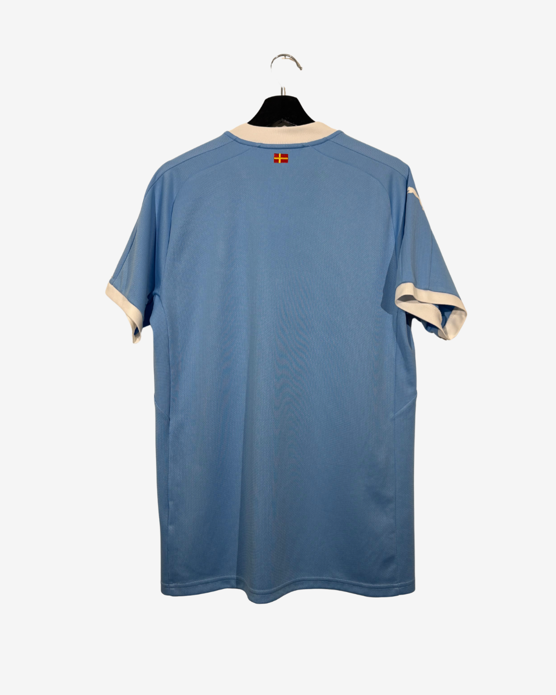 A light blue short-sleeve athletic jersey with cream-colored trim on the collar and sleeve cuffs, hanging on a black hanger against a light gray background.