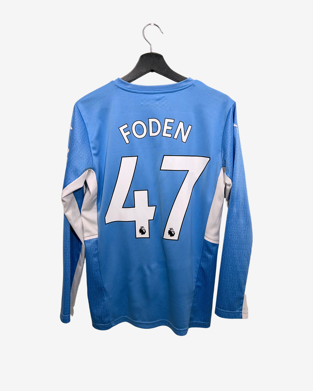 Blue sports jersey with 'FODEN' and number '47' on a hanger against a white background