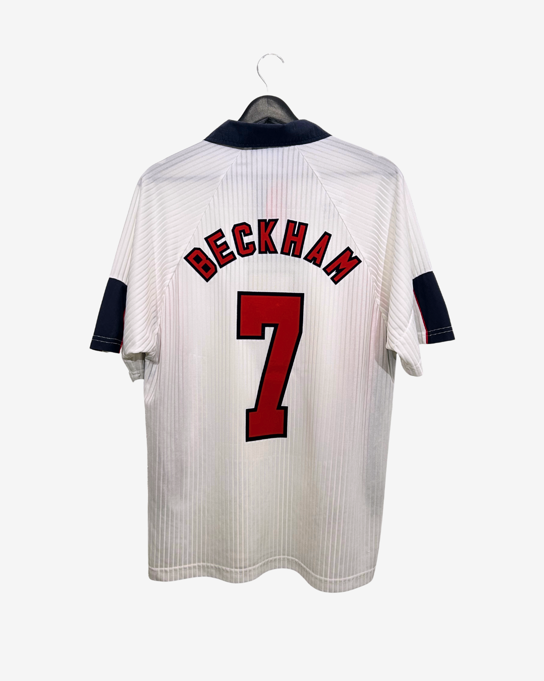White sports jersey with 'Beckham' and number '7' on a hanger against a white background