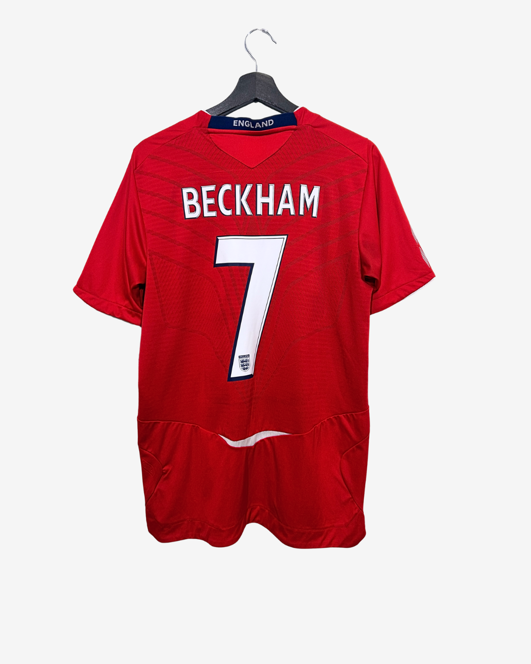 Red sports jersey with 'Beckham' and number '7' on a hanger against a white background