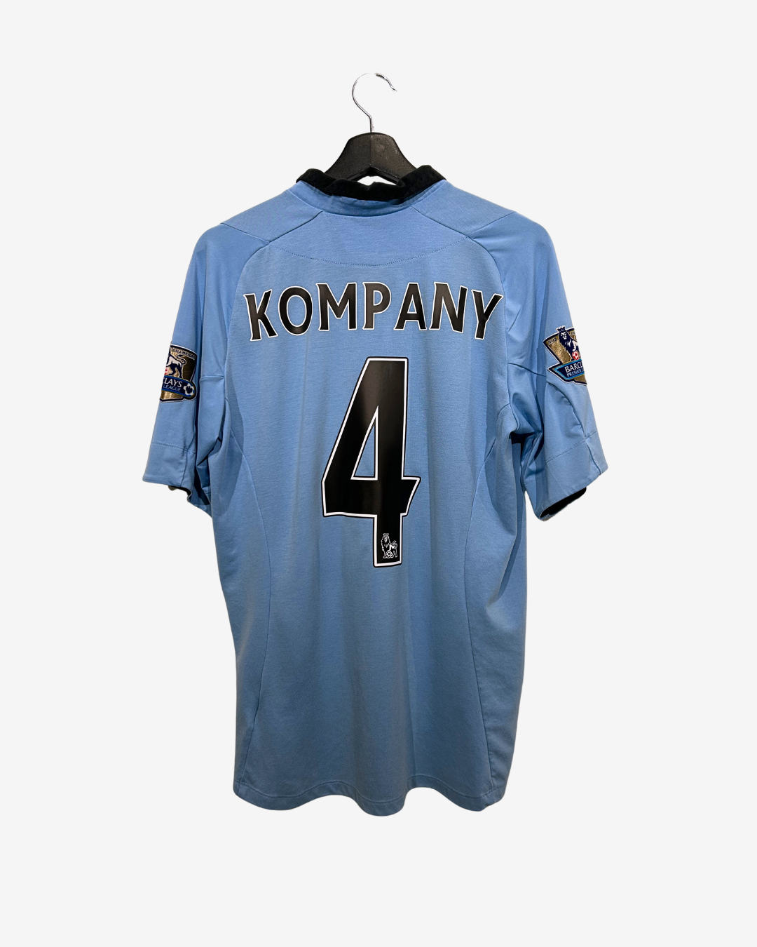 Light blue sports jersey with 'KOMPANY' and number '4' on a hanger against a white background