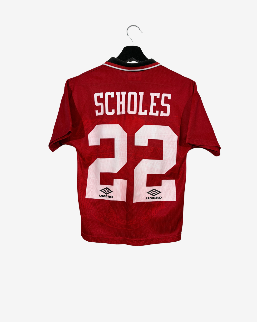 A red short-sleeve soccer jersey hanging on a black hanger against a light gray background. The back of the jersey features the name 'SCHOLES' and the number '22' in white, with Umbro logos printed below the numbers.