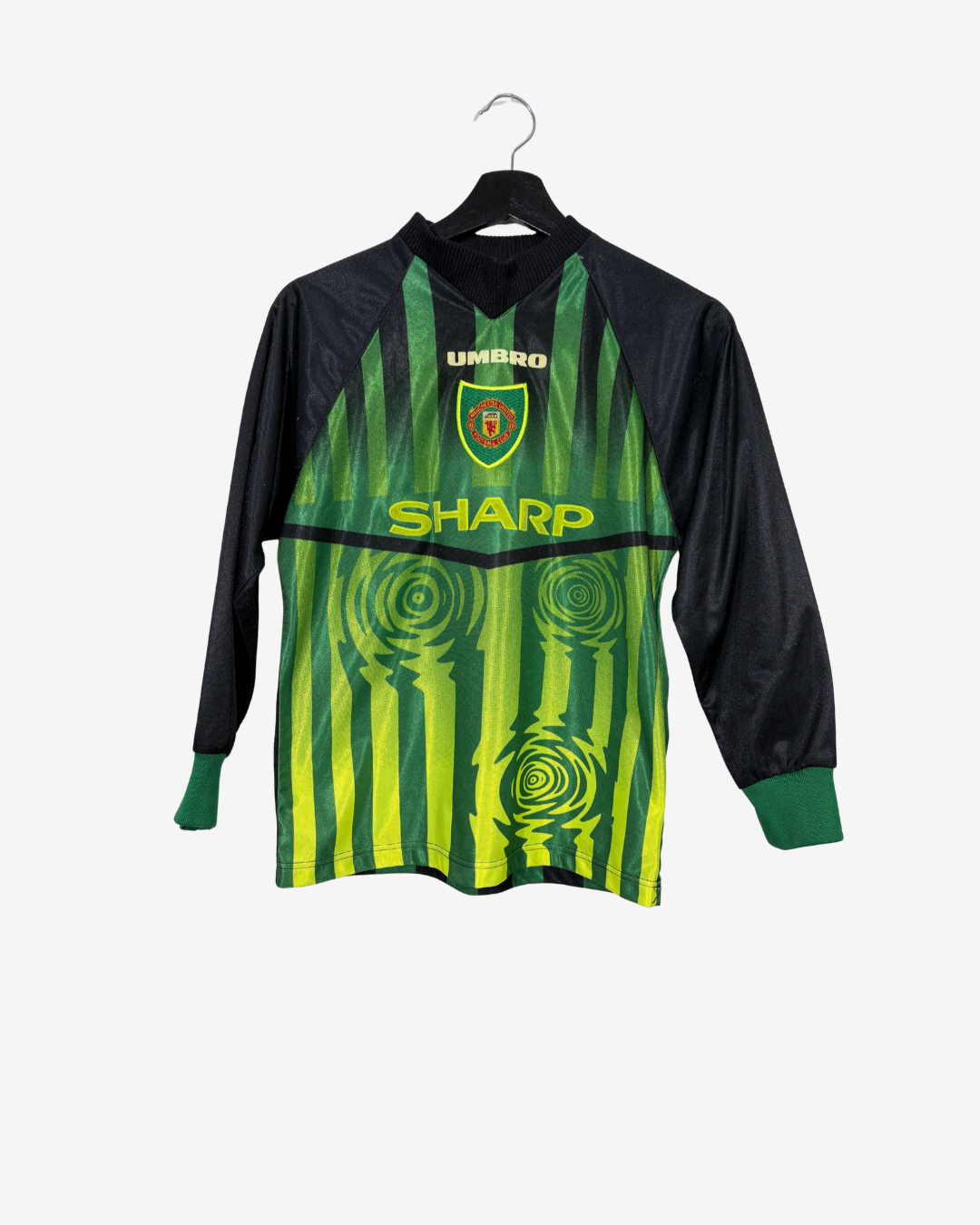 A vintage Umbro long-sleeve soccer jersey in green and black, featuring vertical stripes and spiral patterns, hanging on a black hanger against a light gray background.