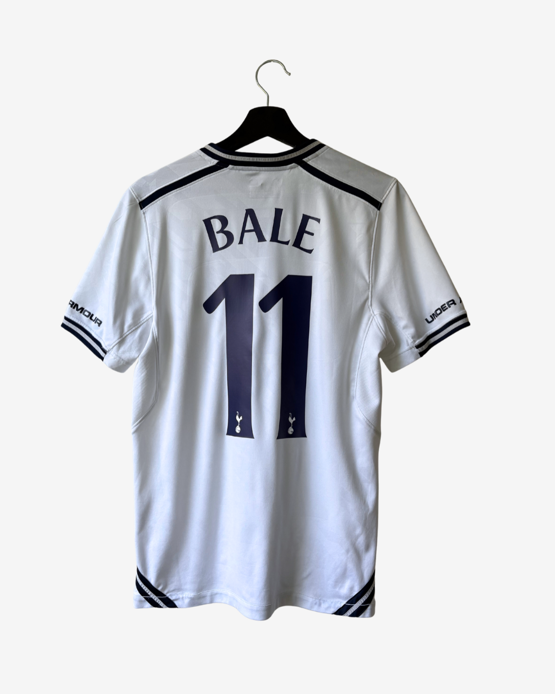 White Tottenham Hotspur football jersey with 'BALE' and number '11' printed in navy blue on the back, hanging on a black hanger against a light gray background.