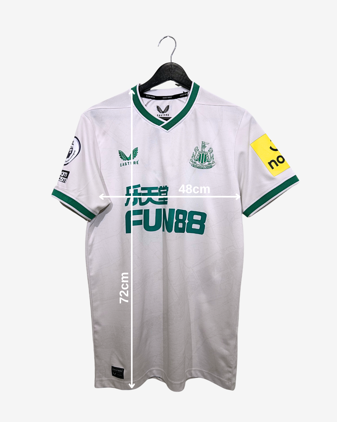 White sports jersey with green accents on a hanger, featuring measurements and branding.